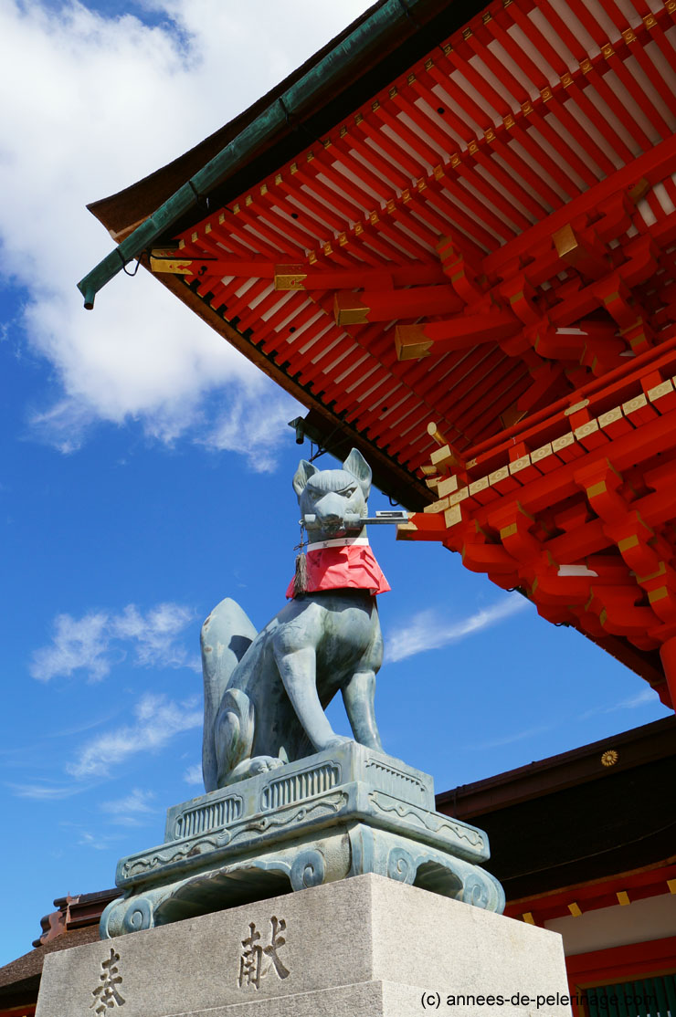 A bronce fox statue with a tool to harvest rice at fushimi inari taisha shrine in Kyoto, Japan