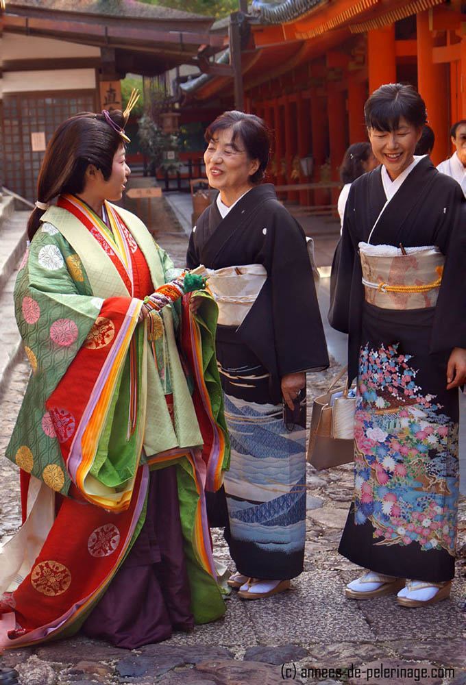 An woman wearing a junihitoe and two japanese women in formal black kimono