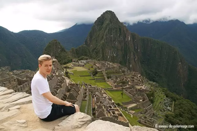 Me sitting on a wall above machu picchu: top destination in my peru itinerary