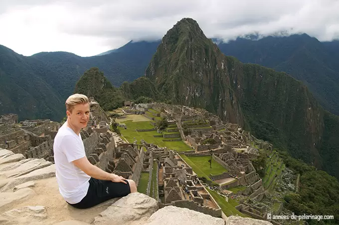 Me sitting on a wall above machu picchu: top destination in my peru itinerary. I packed a lot of light weighted hiking gear for machu Picchu and settled for cotton shirts and short fast drying trekking pants