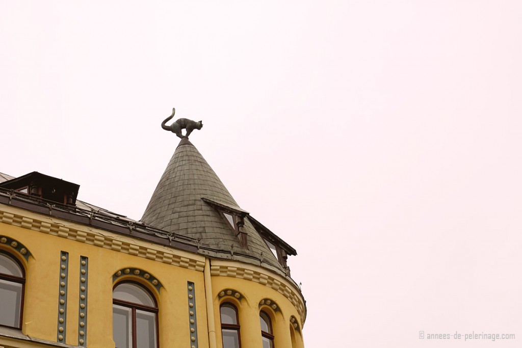 The yellow cat house in riga, with a bronze cat perched on the tip of the tower