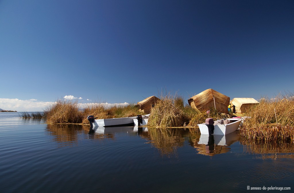 Floating island of the Uros people with small motorboats tied to the reeds