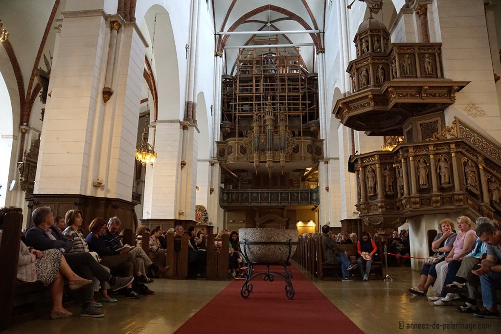 The inside of riga cathedral with the organ and people listenting to the organ concert