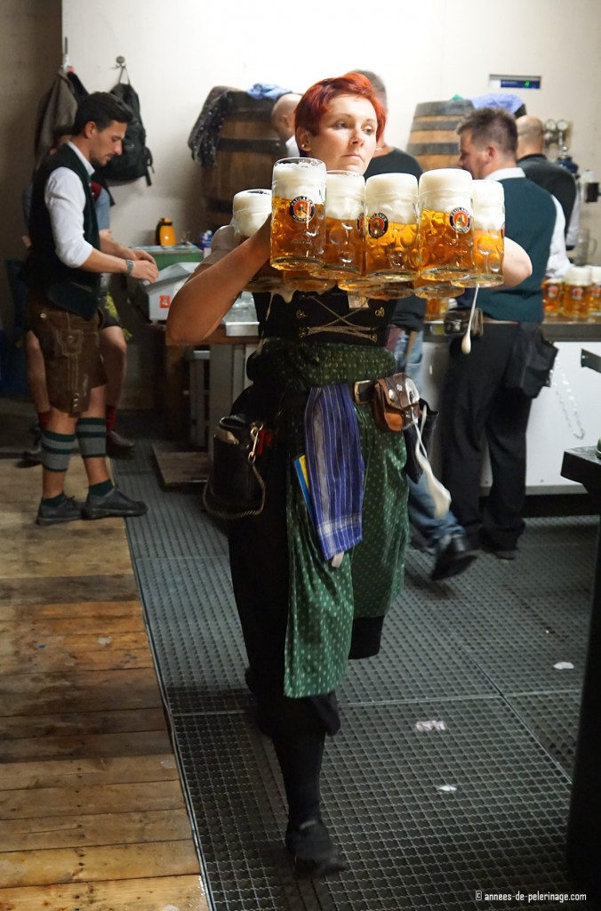 A waitress carrying more than 10 beer mugs at oktoberfest - each weighing almost 1 kilogramm