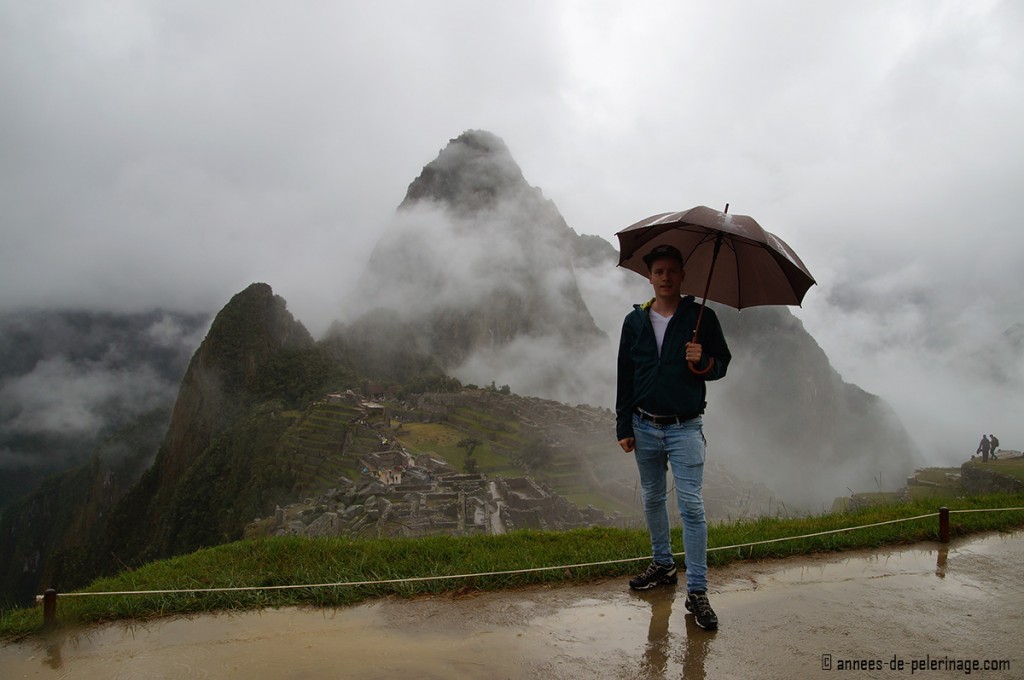 Me standing in Machu Picchu holding an umbrella with heavy rains making the paths very muddy