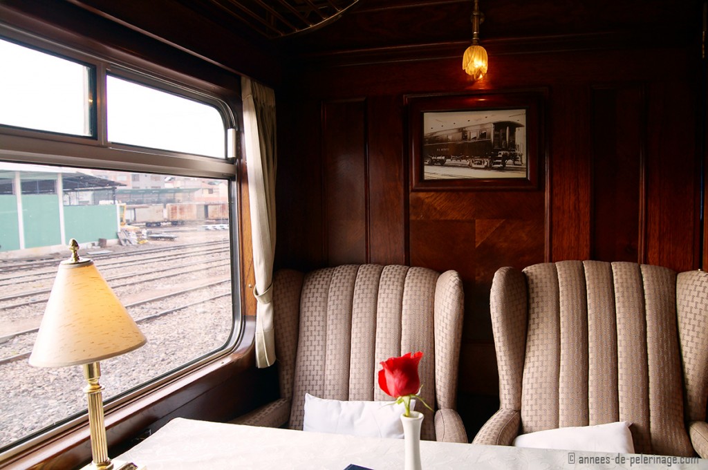 The plush armchair like seats onboard the Andean Explorer Luxury train, with dark wooden panels behind.