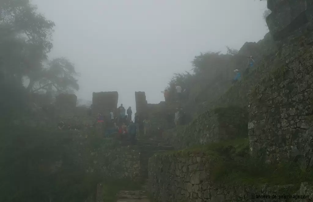 The sun gate over looking Machu Picchu hidden behind heavy fog