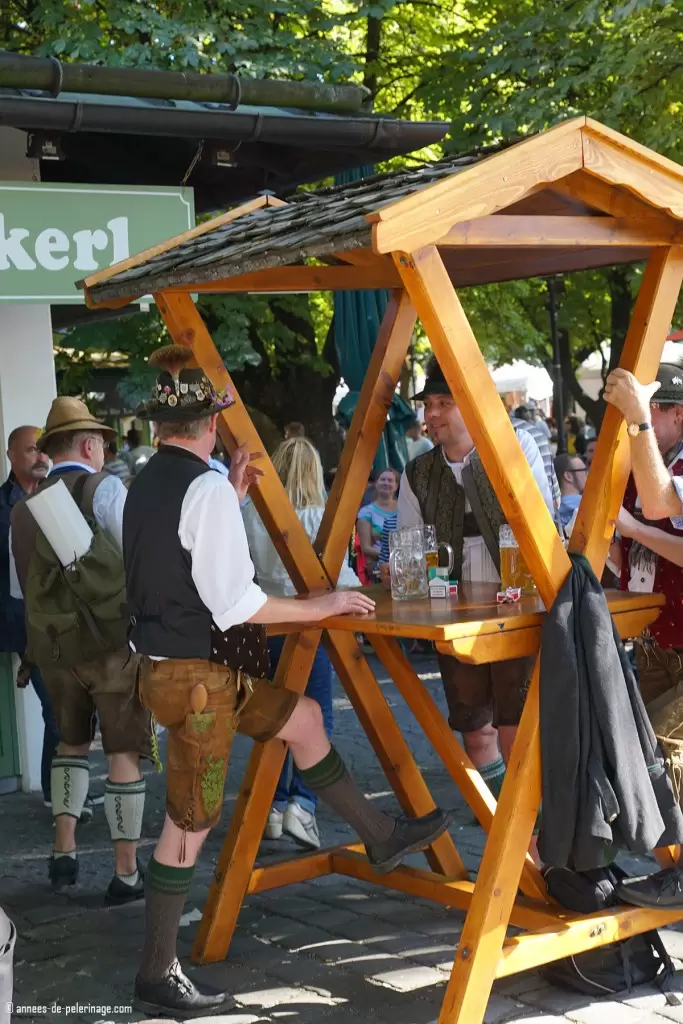 Locals drinking beer in the beergarden on Viktualienmarkt in Munich wearing traditional bavarian cloths