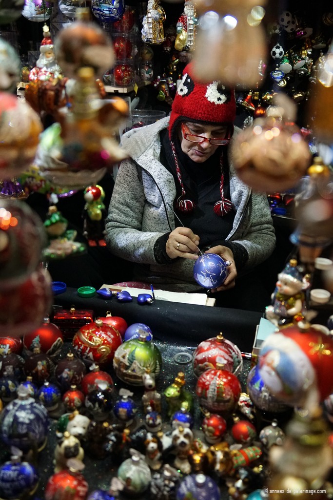 A woman painting christmas tree balls on the Christmas market in Munich