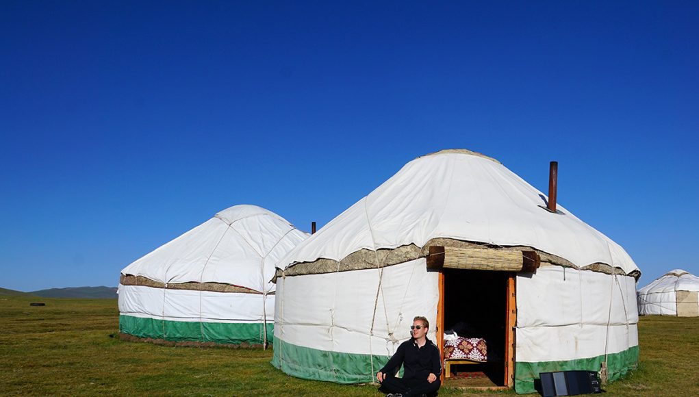 Me sitting in front of a yurt in Kyrgyzstan and my solar panel charging my mobile phone