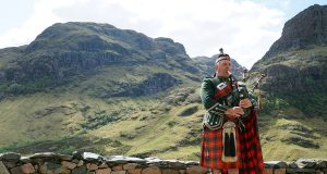 Glen Coe in Scotland and man playing bag pipes