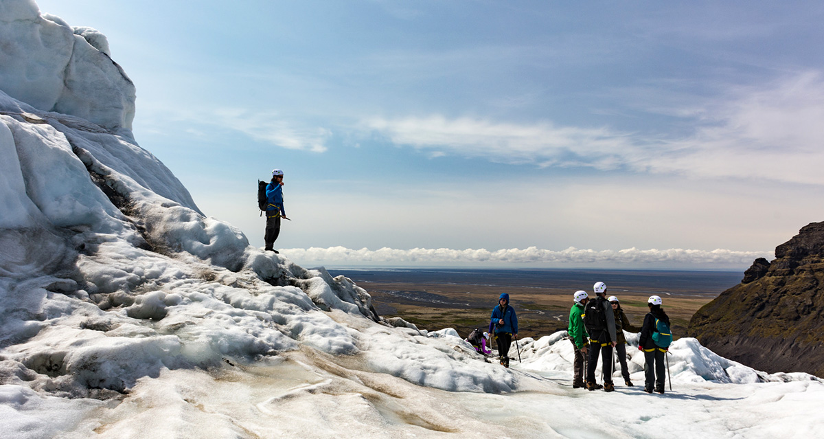 A group of travelers on a glacier hike in iceland, all wearing glacier hiking boots and crampons