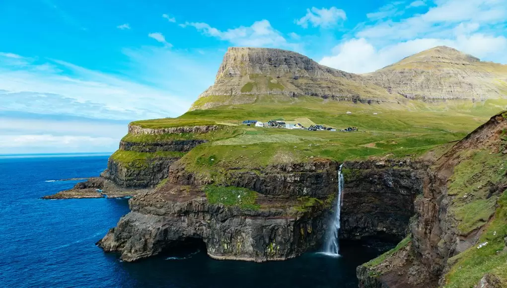 Gásadalur village with the high cliffs and the waterfall dropping into the ocean. One of the main points of interest Faroe Islands