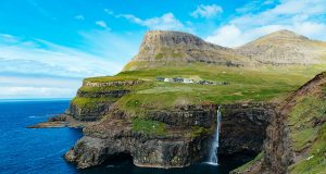 Gásadalur village with the high cliffs and the waterfall dropping into the ocean. One of the main points of interest Faroe Islands