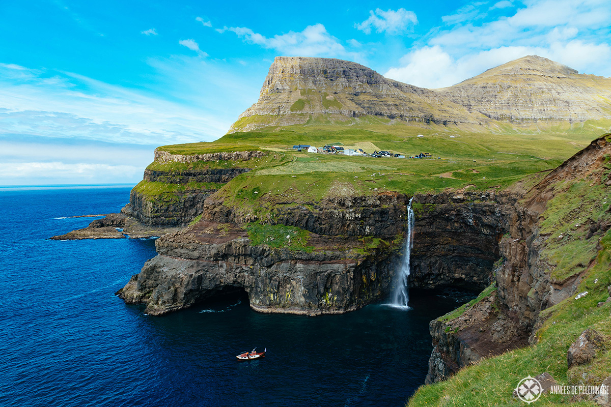 Gásadalur village with the high cliffs and the waterfall dropping into the ocean. One of the main points of interest Faroe Islands