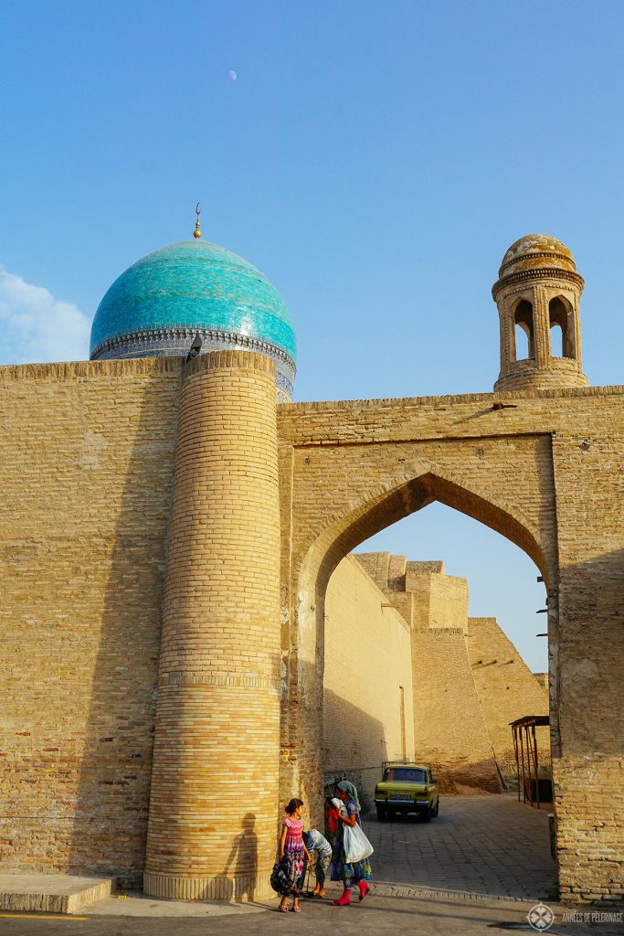 A street scene with three girls playing under an ancient arch in Bukhara Uzbekistan