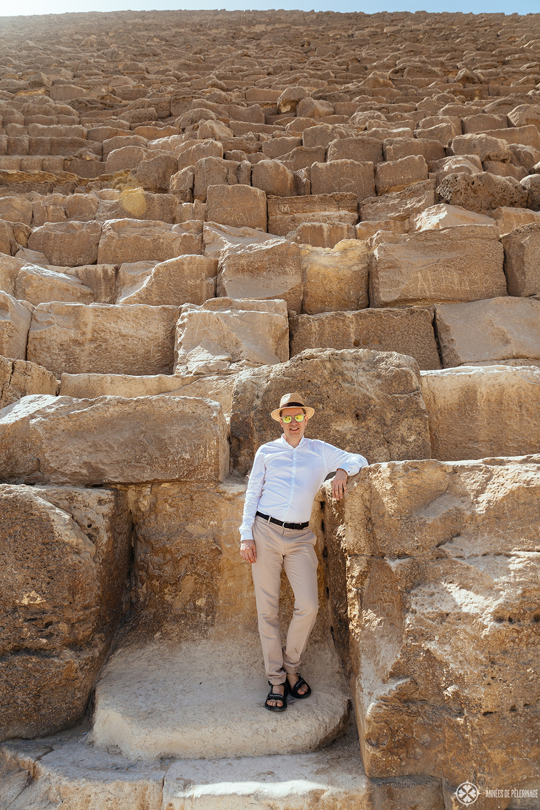 Me standing at the base of the Great Pyramid of Khufu - you can't climb them but that doesn't mean you can't get a great picture when visiting the pyramids in Egypt