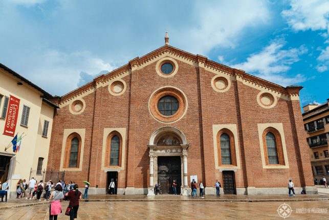 The entrance of the Last Supper Museum is on the left of the Church (where the flags are hanging down) of Santa Maria delle Grazie in Milan, Italy