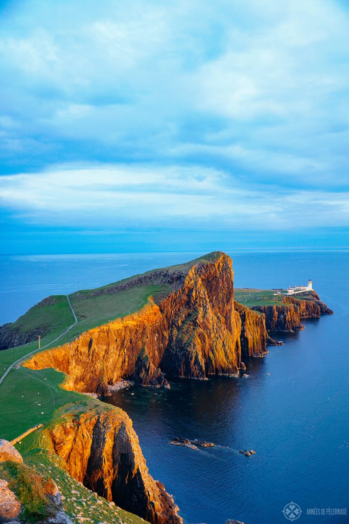 An epic sunset mood at the Neist Point Lighthouse with deep orange cliffs on the Isle of Syke, Scotland