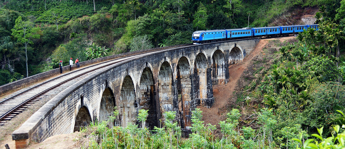 Blue train driving across Nine Arch Bridge near Ella - a tourist's favorite and a must on any sri lanka itinerary