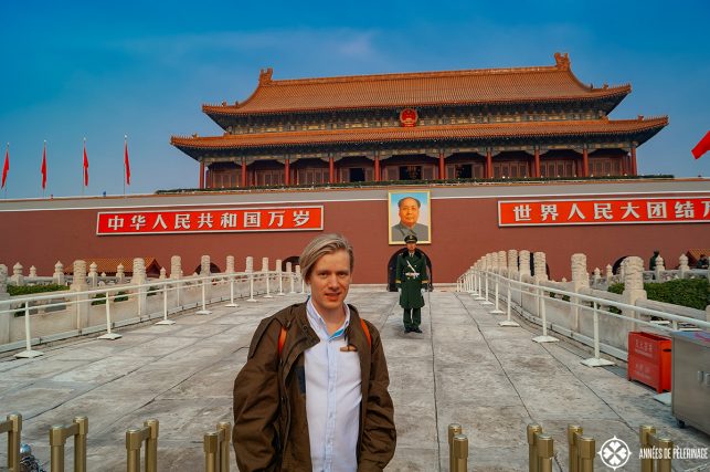 Me standing at the entrance of the Forbidden City in Beijing - a policeman and mao's portrait in the back