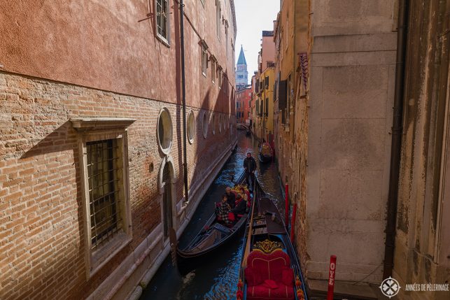 a couple of gondolas with tourists navigating through a particular narrow water channel in Venice, Italy