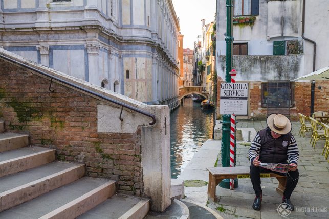 a gondolier waiting for customers in front of a sign saying "gondola service"