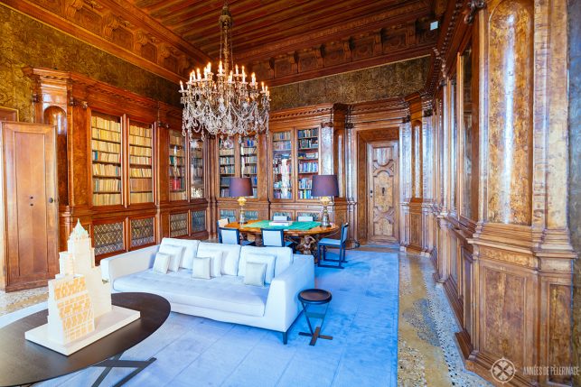 The ancient library on the second floor of AMan Venice, with leather tapestries and ornate wooden book cases