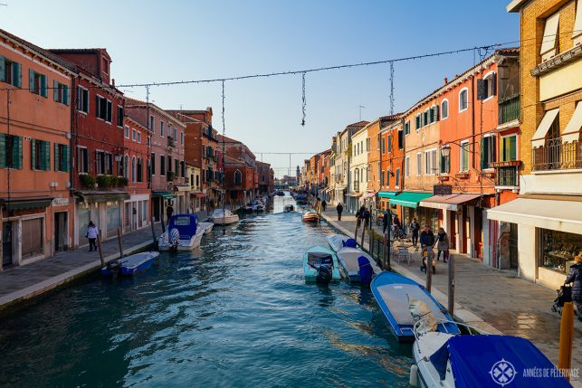 View of a smaller water channel on the Island of Murano from one of the bridges with colorful houses (mostly tones of red and ochre) on each side