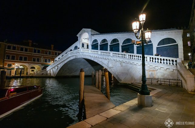 The Rialto bridge in Venice at night with a street lantern and a little empty board pier in the foreground