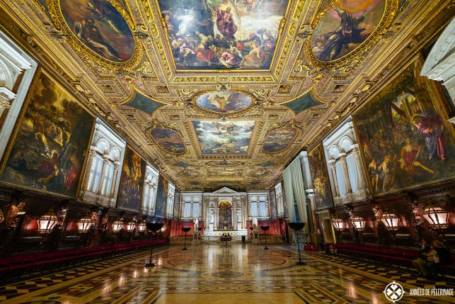 The grand chapterhouse hall on the second floor of the Scuolla grande di San Rocco in Venice with an ornate golden ceiling and religious paintings by tiepolo