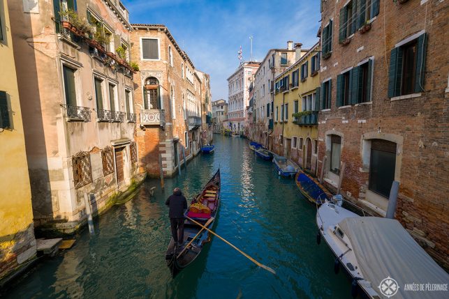 A traditional gondola in Venice italy on a smaller waterway with lots of colorful houses