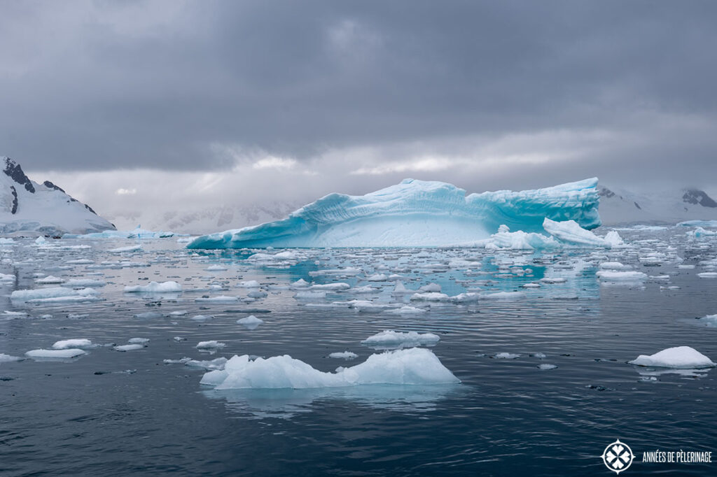 a stark blue iceberg floating in the waters around antartica