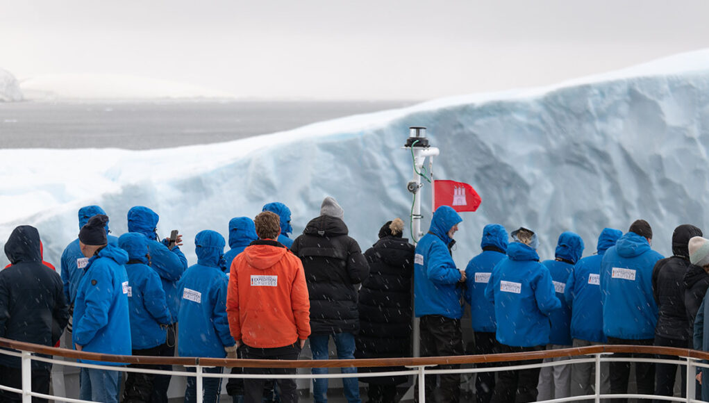 passengers on spirit walk passengers standing on the bow of a cruise ship to touch an ice berg