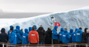 passengers standing on the bow of a cruise ship to touch an ice berg