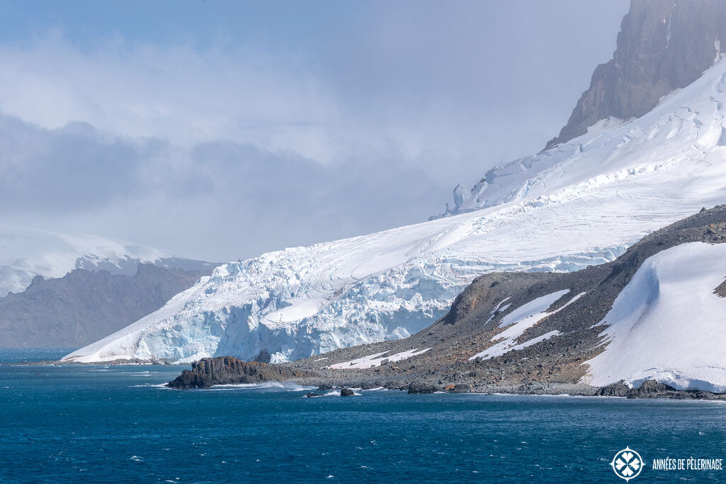 a rugged coast with a huge glacier melting into the antartic water