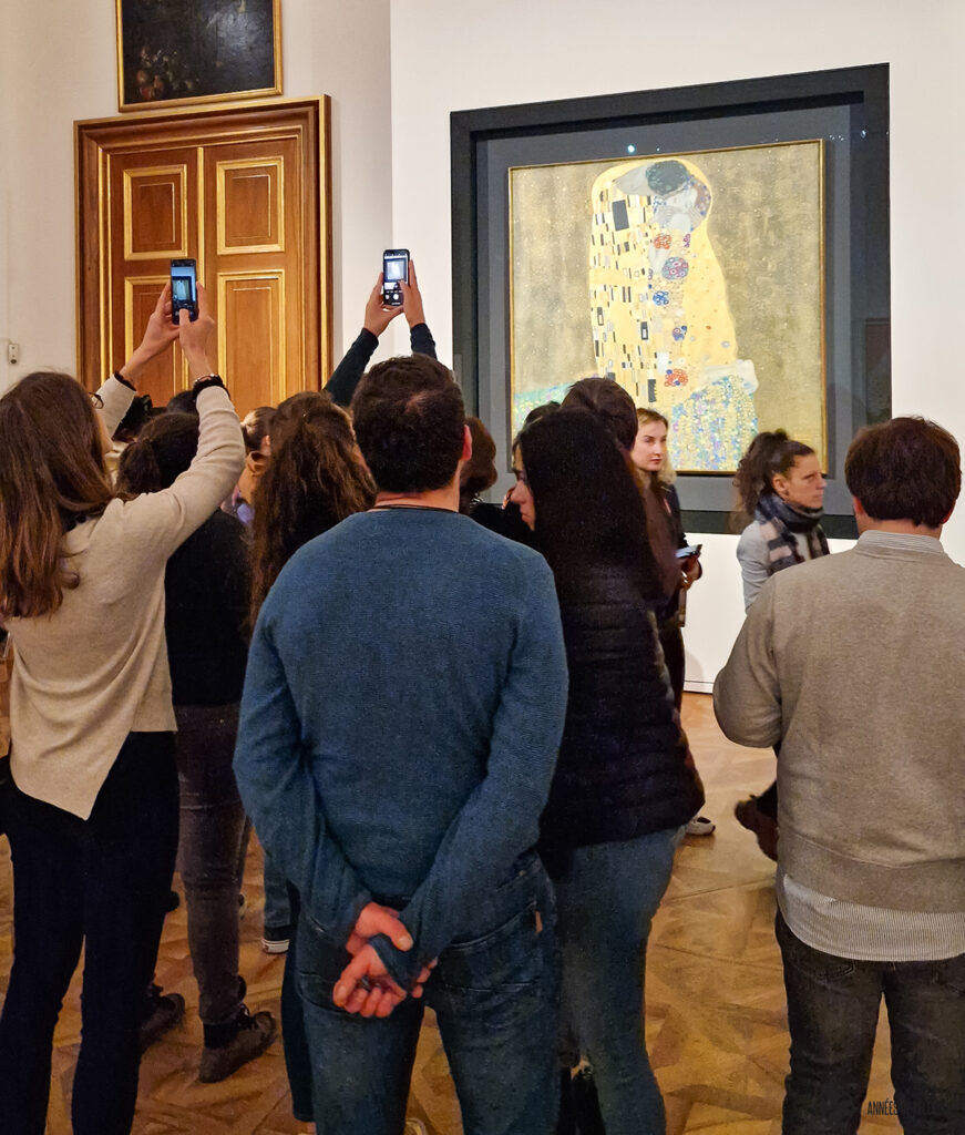 a crowd standing in front of gustav klimt's "The kiss" in vienna